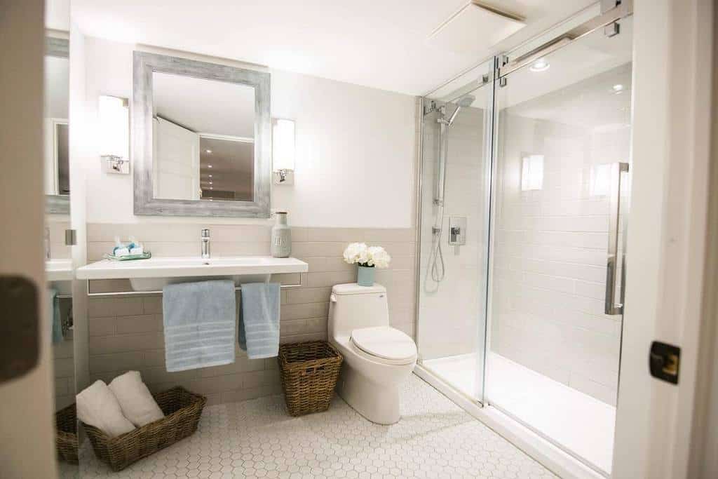 Cozy wet room with a glass-enclosed shower, floating vanity, soft lighting, and wicker storage baskets for a warm and inviting feel