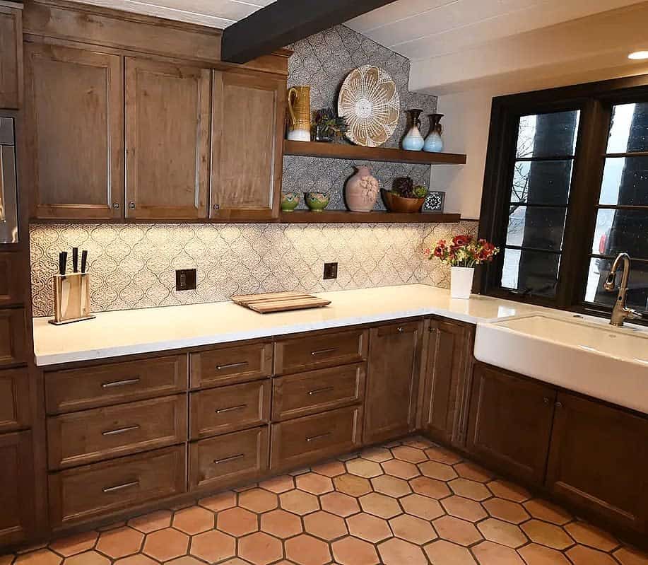 Dark wooden floating shelves display ceramic vases and decorative plates, enhancing the rustic charm of this warm-toned kitchen with tiled backsplash