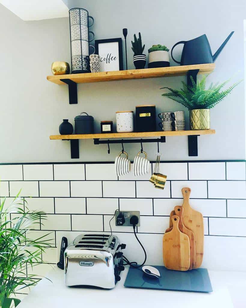 Wooden floating shelves with black brackets display coffee decor, plants, and mugs, adding a modern touch to this stylish kitchen corner