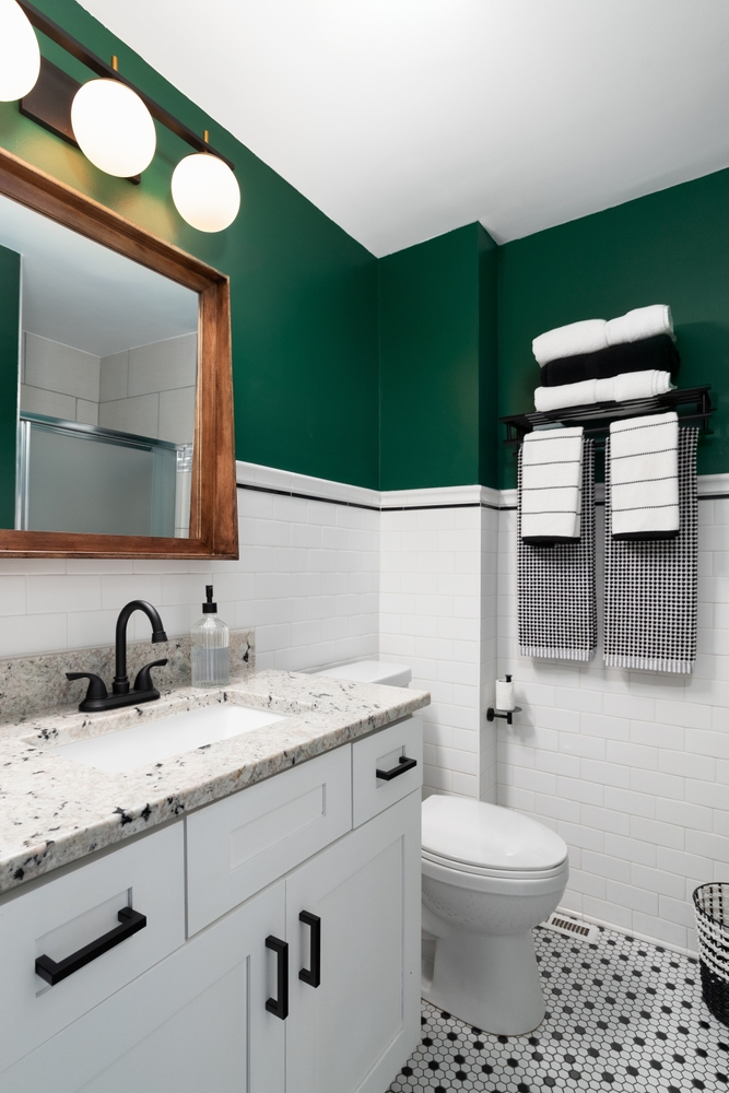 Modern bathroom with green walls, white tiles, and a granite countertop