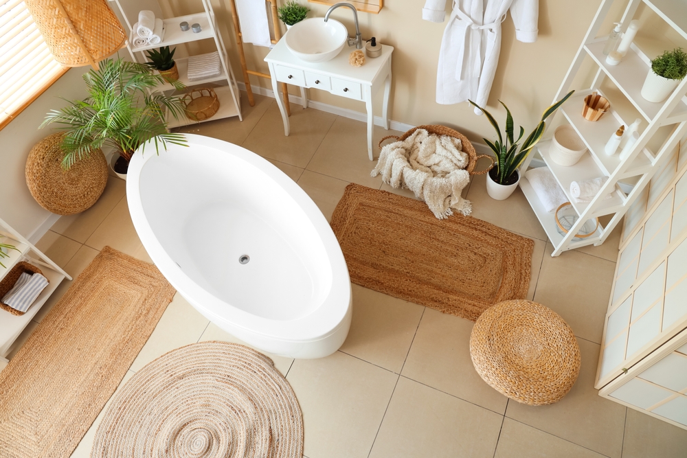 Modern bathroom with a white oval bathtub, rugs, plants, and various storage units.