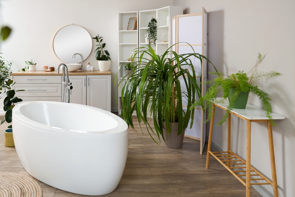 Modern bathroom with a freestanding tub, plants, and wooden furniture.