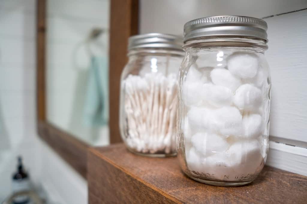 cotton balls and cotton swabs in a mason jars on bathroom with sink