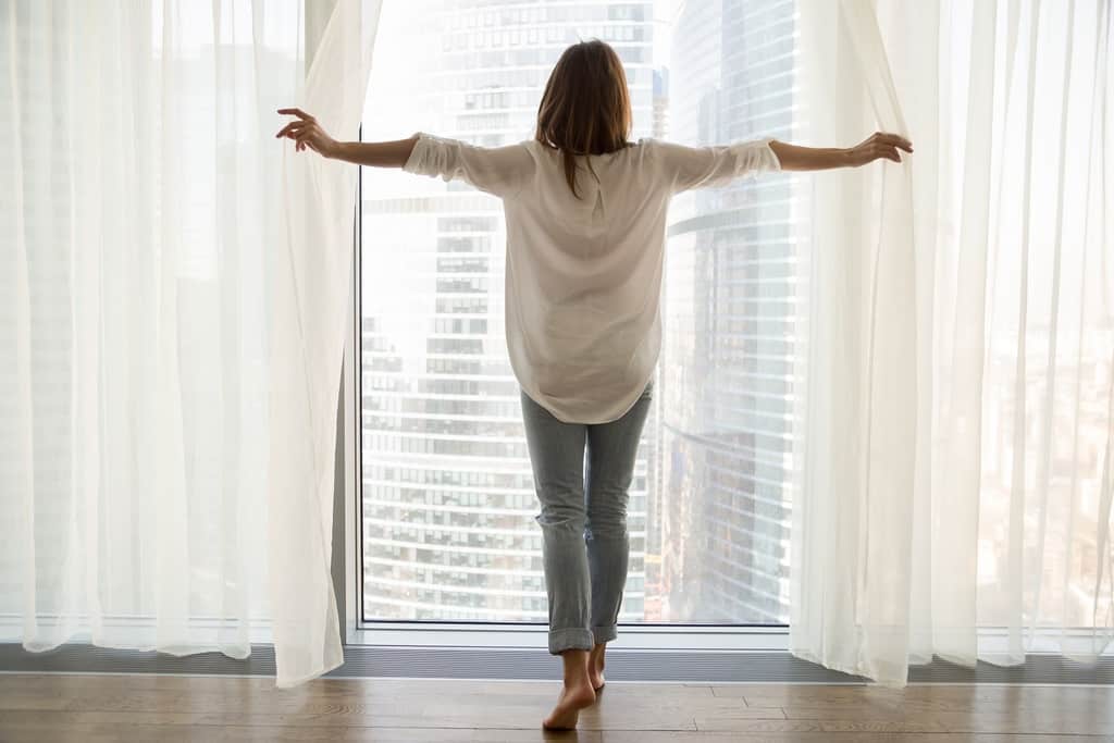 woman standing looking out the window in a modern apartment