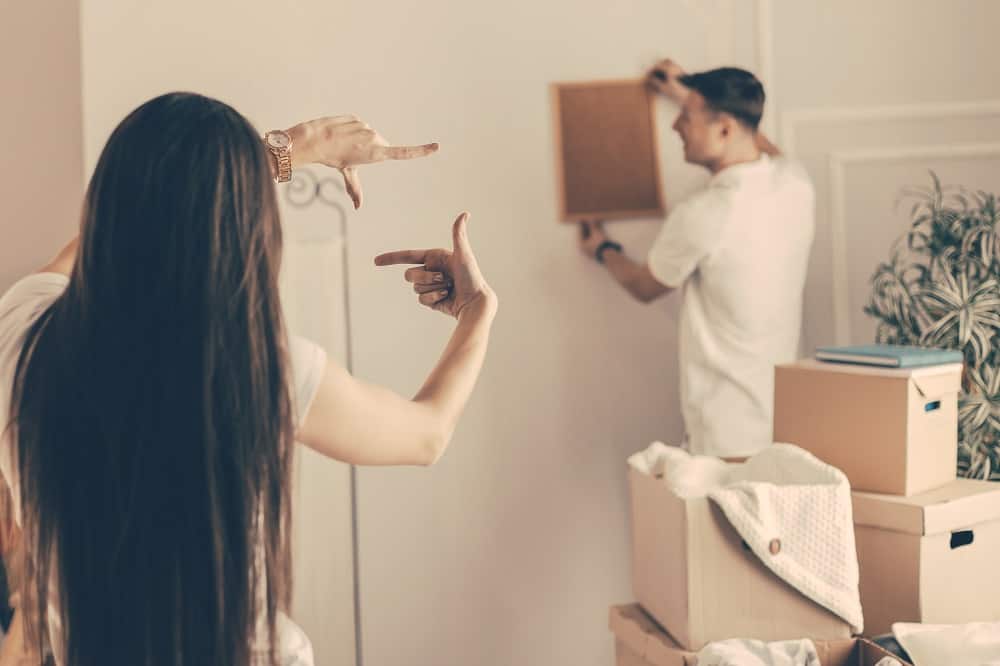 couple arranging photo frames in the wall