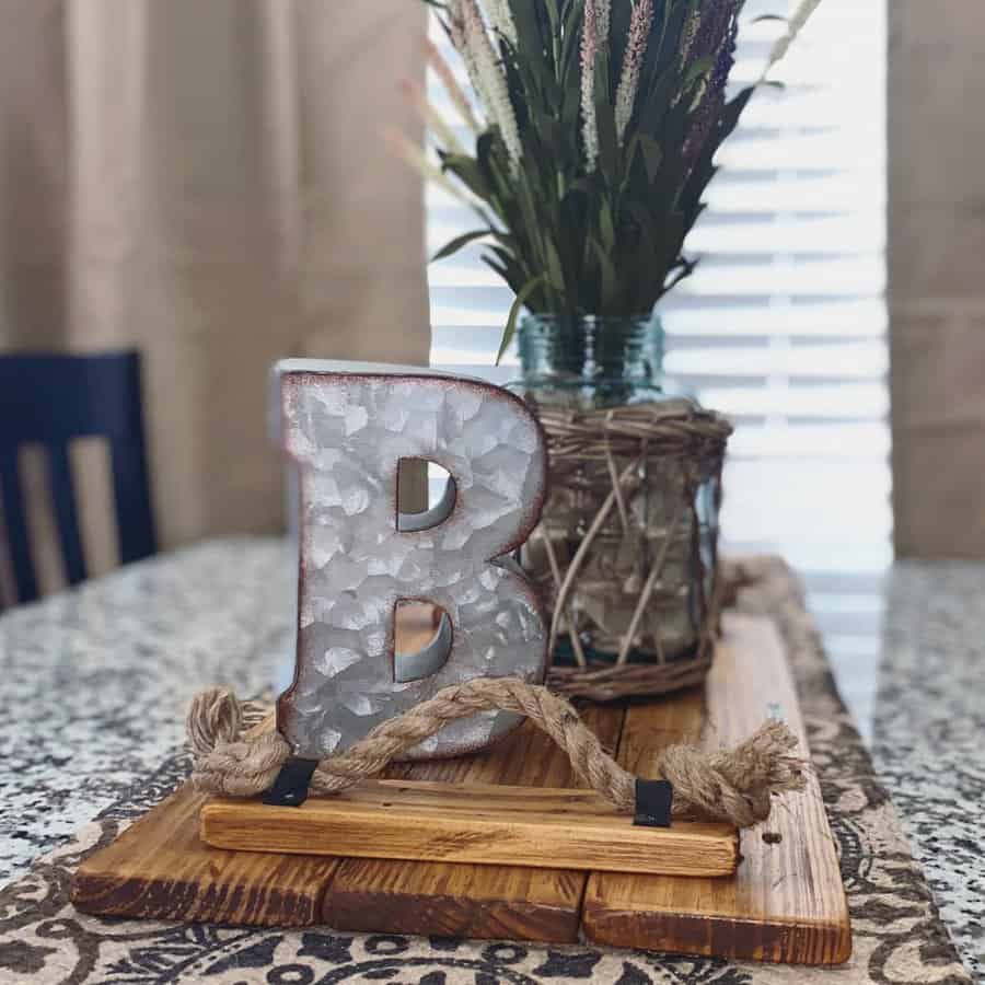 Decorative letter "B" and vase with dried flowers on a wooden tray