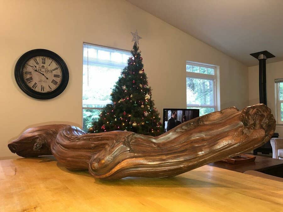 Large, sculptural wooden centerpiece with a natural, organic shape placed on a dining table in a cozy, festive living space