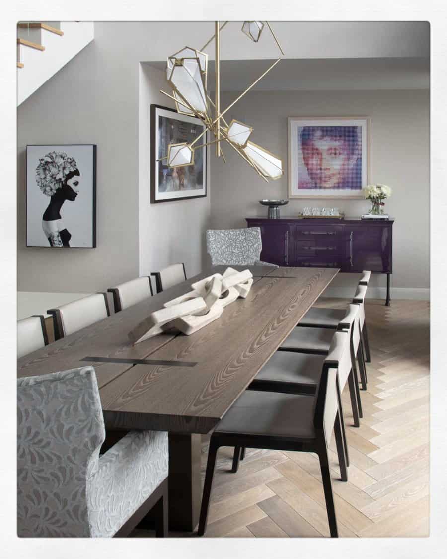 Modern dining room with a sculptural wooden centerpiece on a dark wood table, surrounded by neutral chairs and stylish decor