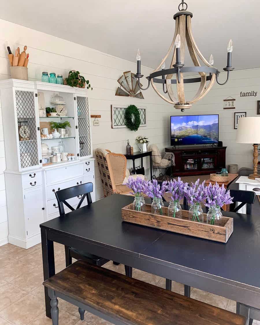 Farmhouse dining room with a black table, rustic wooden tray centerpiece holding glass jars filled with lavender, and cozy decor