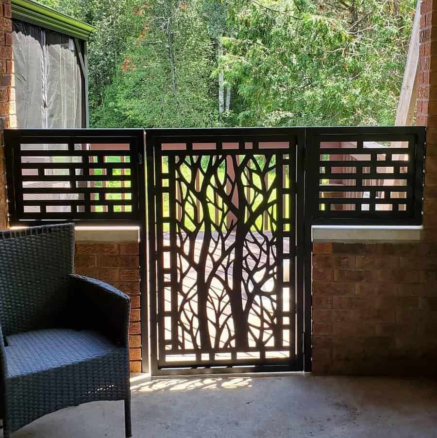 Stylish patio privacy gate with a decorative metal screen featuring a tree design, framed by brick walls, creating a modern and elegant outdoor enclosure