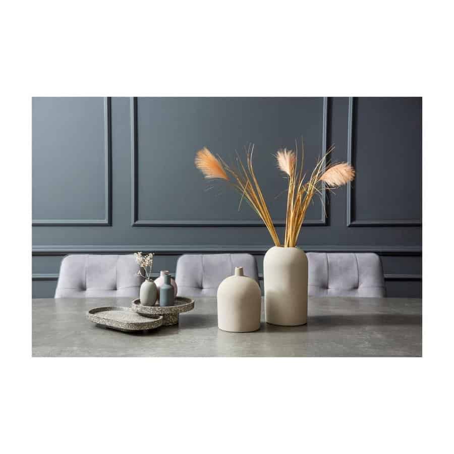 Minimalist dining room with gray walls, table, and chairs featuring beige vases with tall grass for decoration