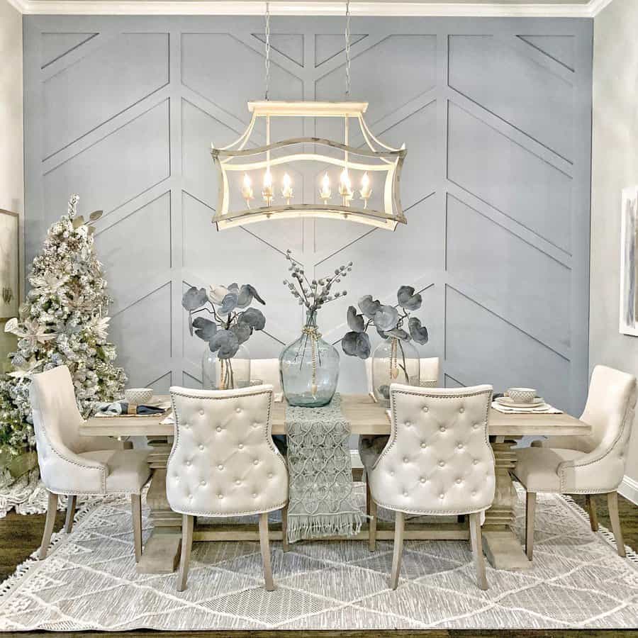 Elegant dining room with tufted chairs, a light wood table, glass vases with greenery, a soft-toned runner, and a statement chandelier