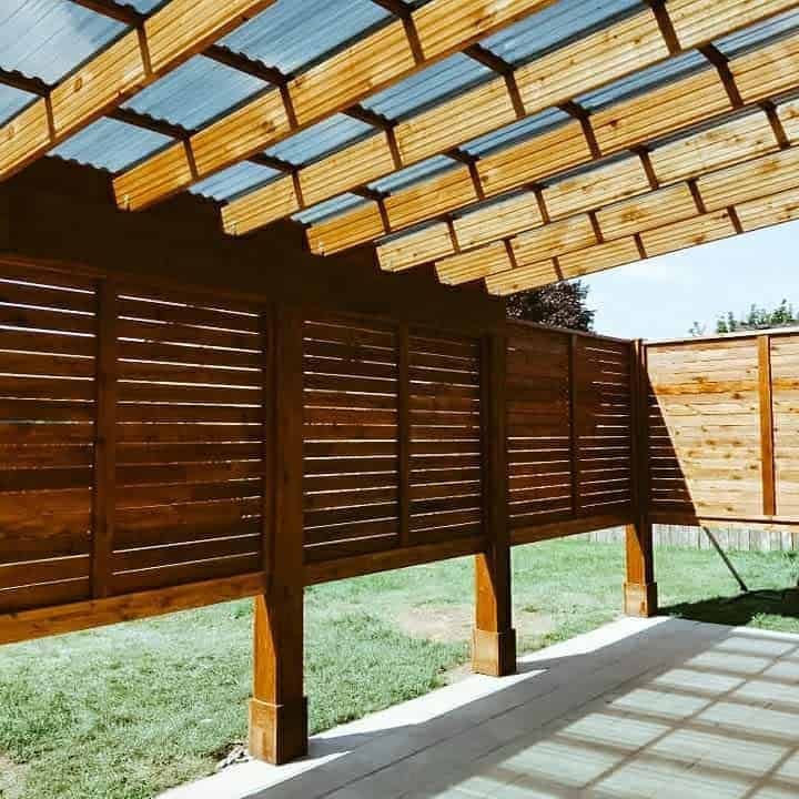 Modern outdoor patio with a wooden slatted privacy screen and a pergola-style roof with translucent panels, providing shade and a stylish enclosed space