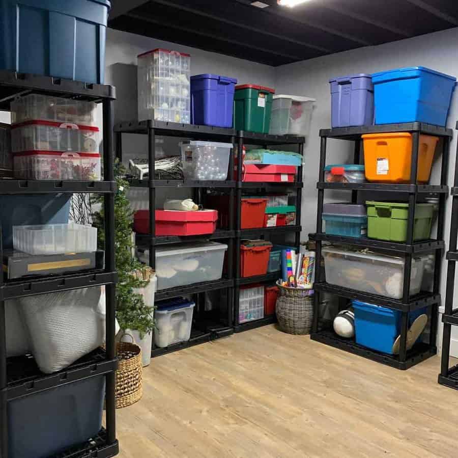 Home storage area with black shelves holding colorful plastic bins and boxes, neatly organized with a wooden floor and a potted plant