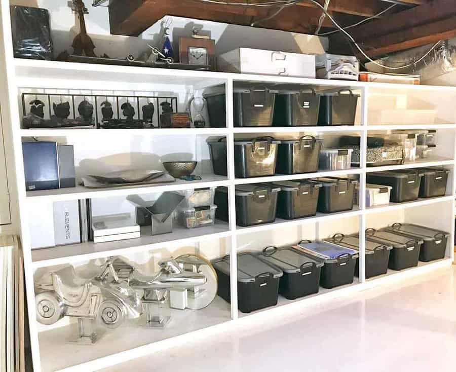 Organized storage shelves with black bins, books, and various items in a basement with exposed ceiling beams