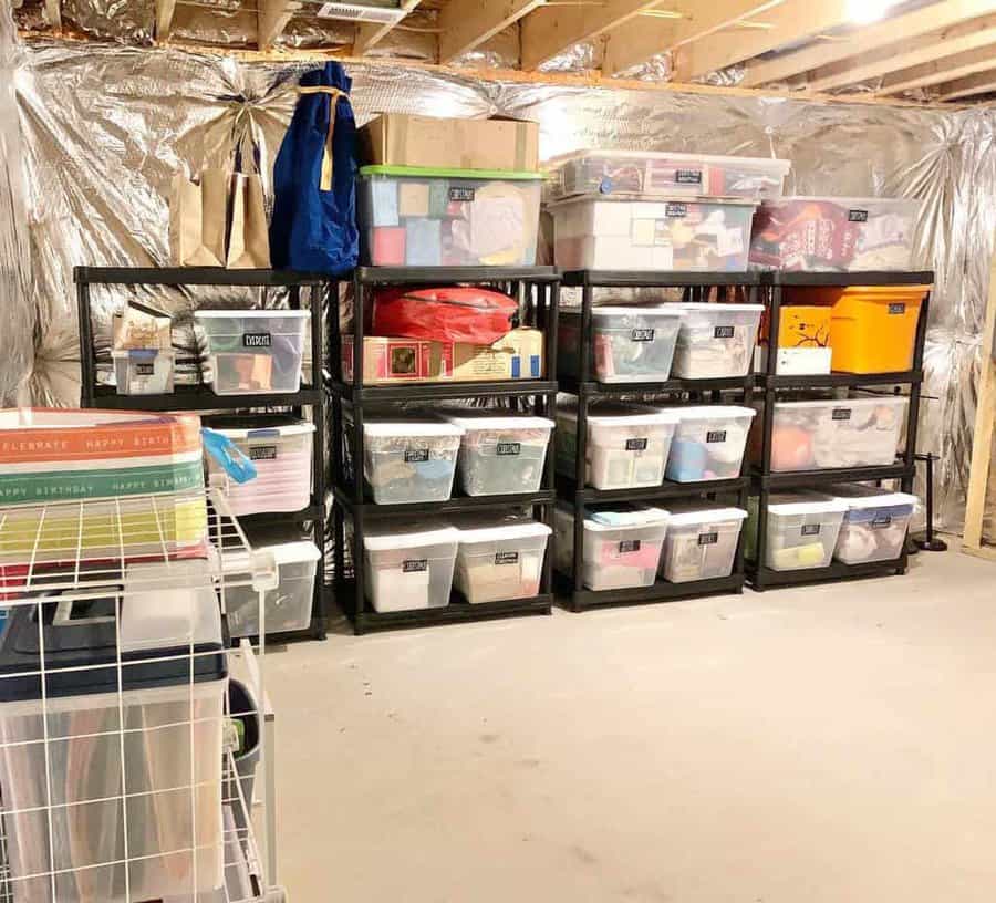 Storage room with plastic bins stacked on black shelves against foil-insulated walls, and gift bags on a wire rack