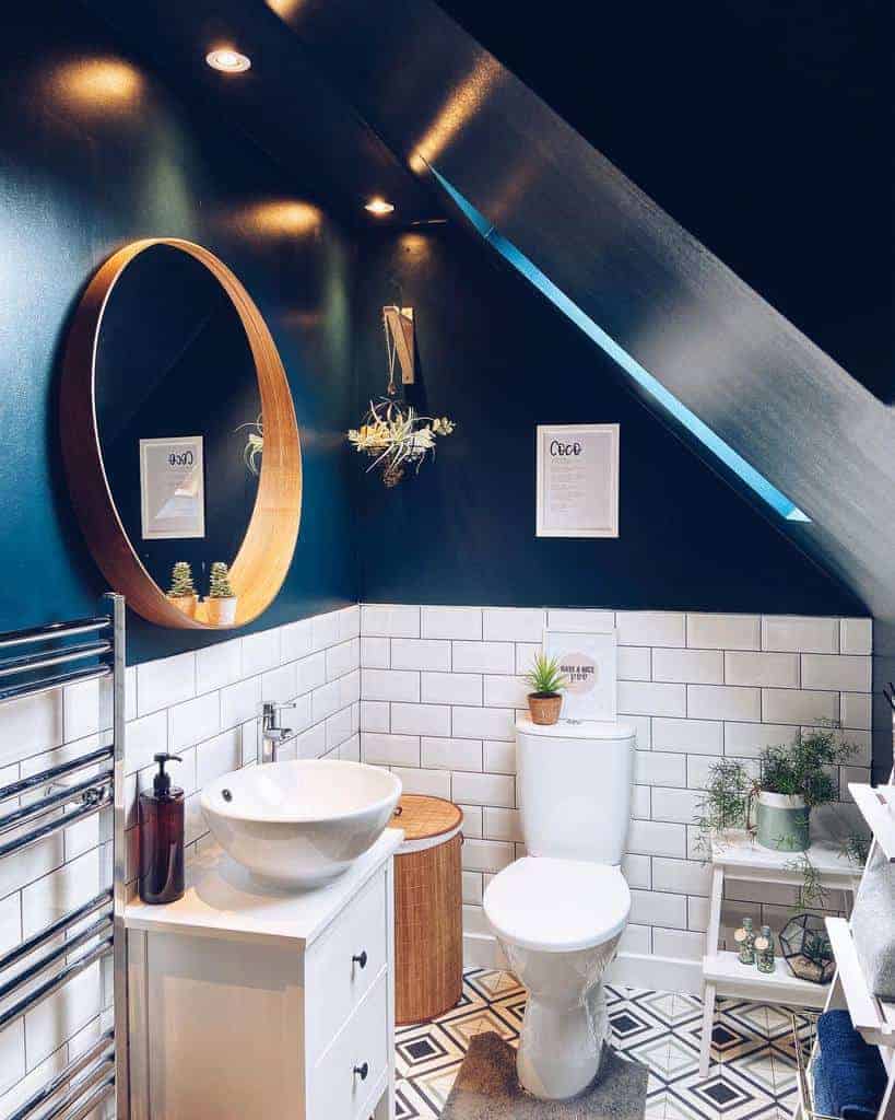 Stylish attic bathroom with navy walls, white subway tiles, a round mirror, and open shelving for a modern and functional storage solution