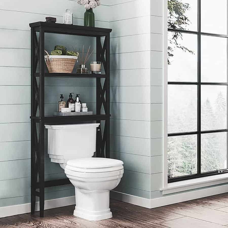 Modern bathroom with a black over-the-toilet storage shelf, holding baskets, towels, and toiletries for a stylish and space-saving solution