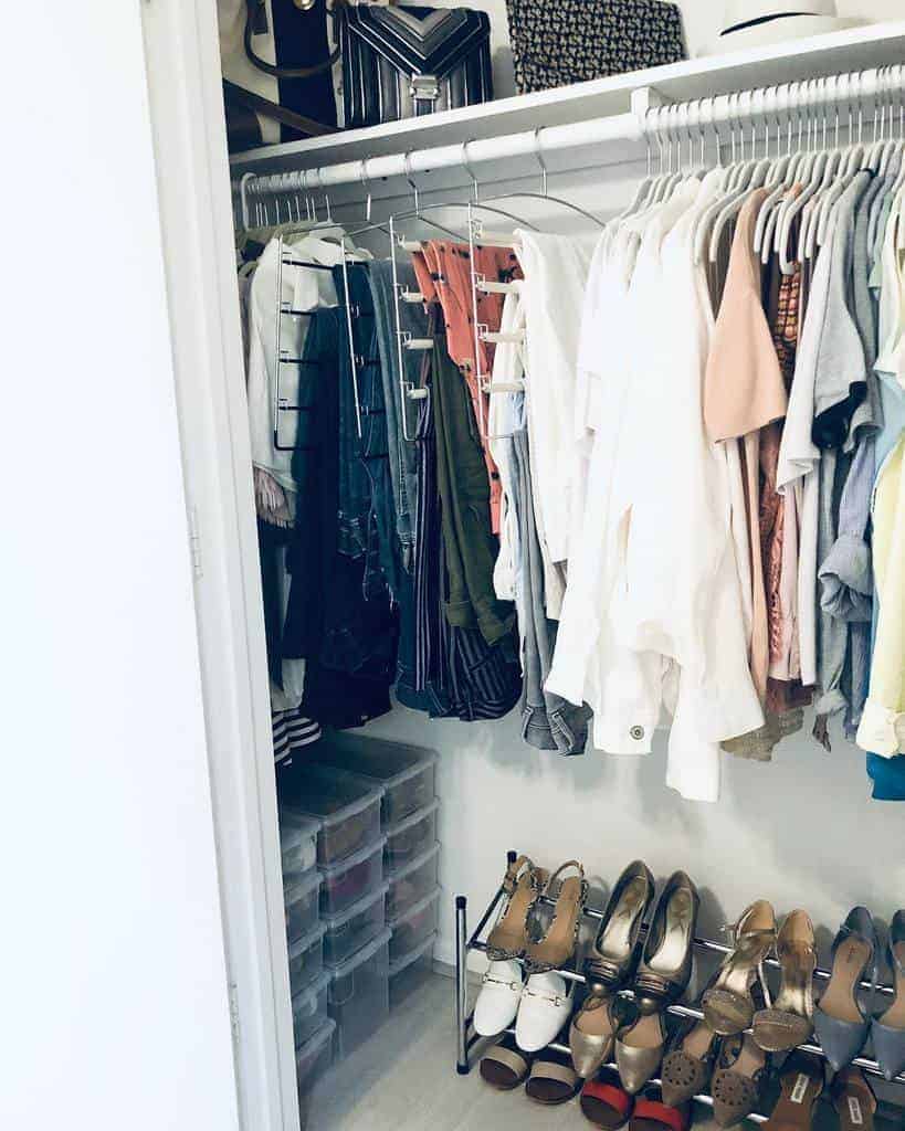 A neatly organized closet with clothes on hangers, shoes on a rack below, and bags on the top shelf