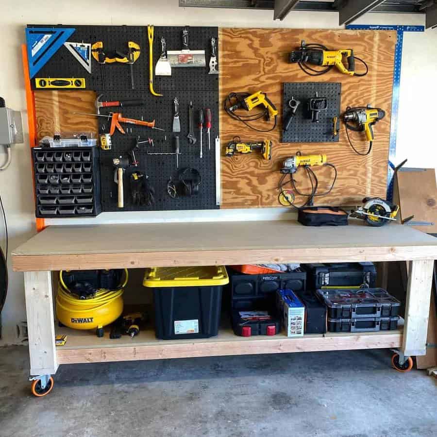 A tidy workbench with organized tools hanging on pegboards above and storage below, including power tools, a toolbox, and a shop vacuum