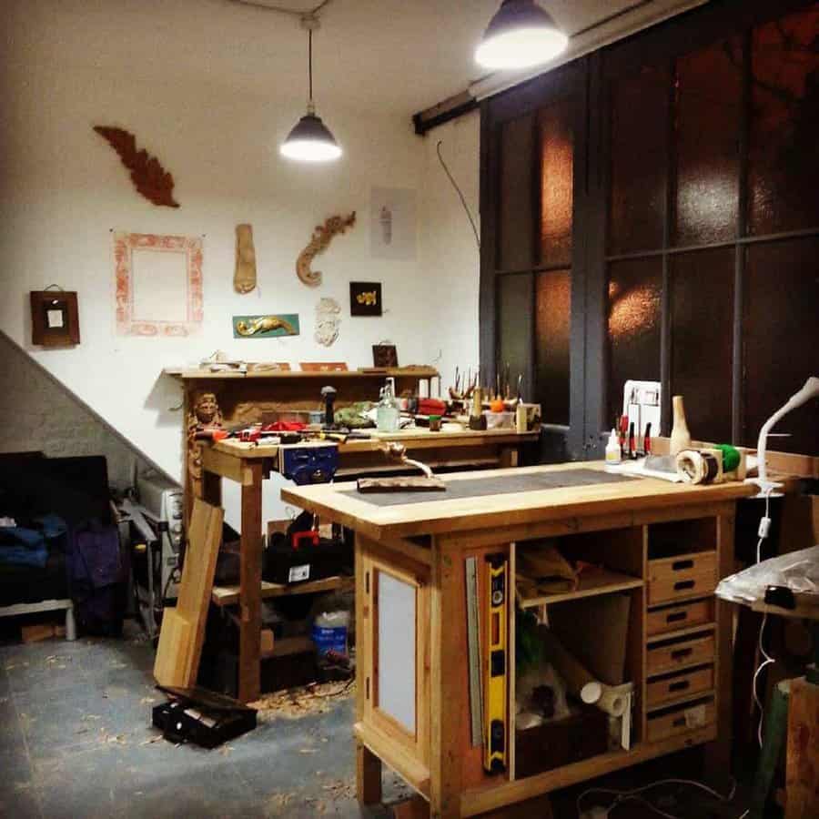 A cozy woodworking workshop with tools, wooden pieces, and a workbench, softly lit by overhead lamps