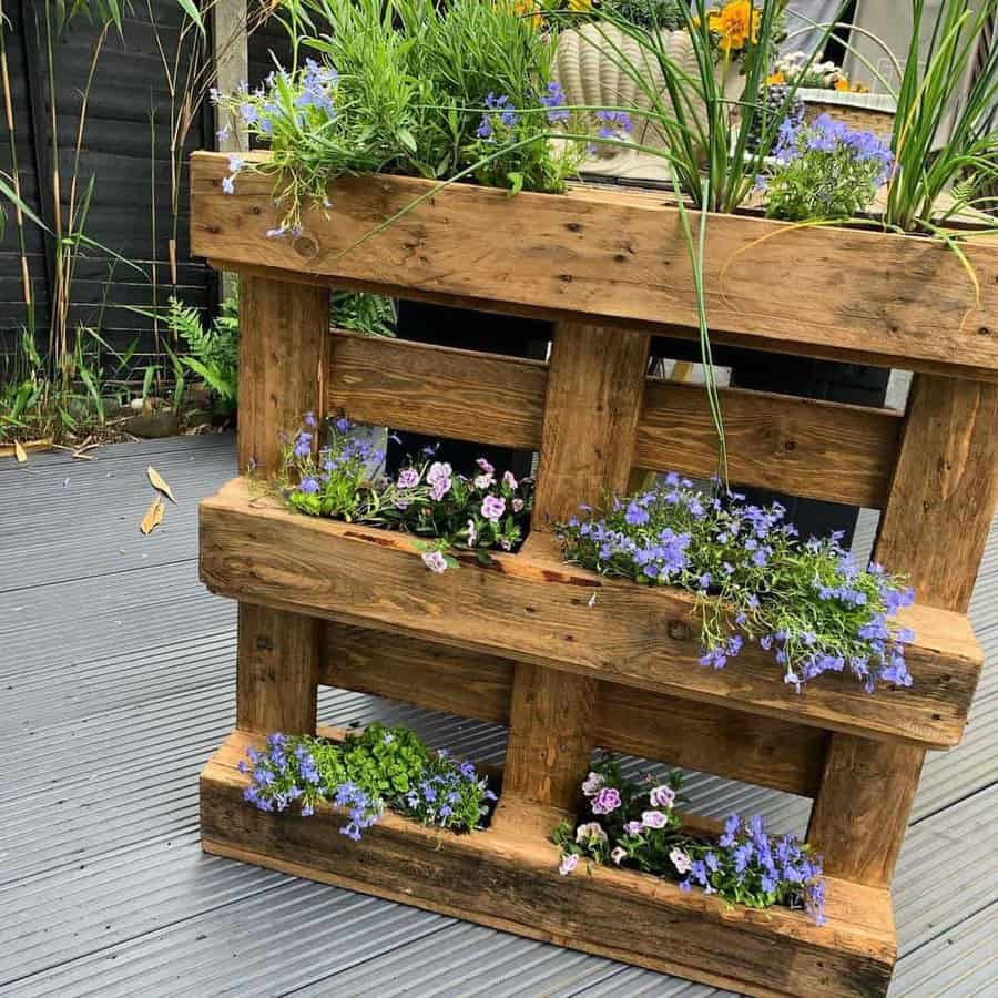 Rustic wooden pallet planter filled with vibrant purple and green flowers, set on a modern deck for a stylish vertical garden display