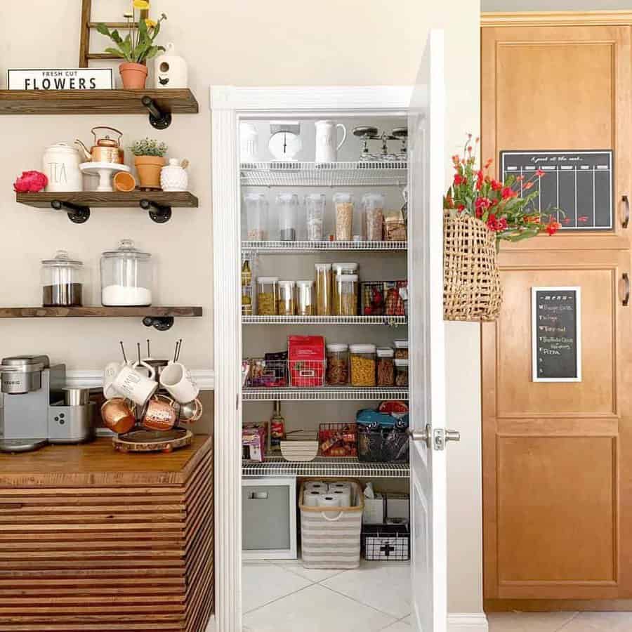 A well-organized pantry with shelves of jars, cans, and baskets; nearby, wooden shelves hold a coffee maker and mugs