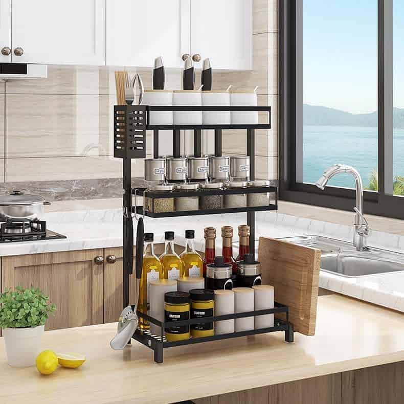 A tidy kitchen with a countertop spice rack holding condiments, spices, and kitchen tools near a large window with a sea view