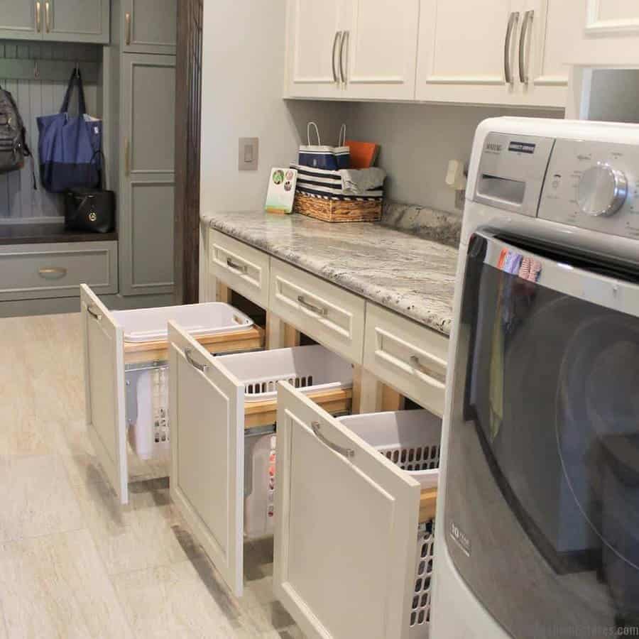 Laundry room with front-loading washer, granite countertop, storage cabinets, and pull-out laundry basket drawers