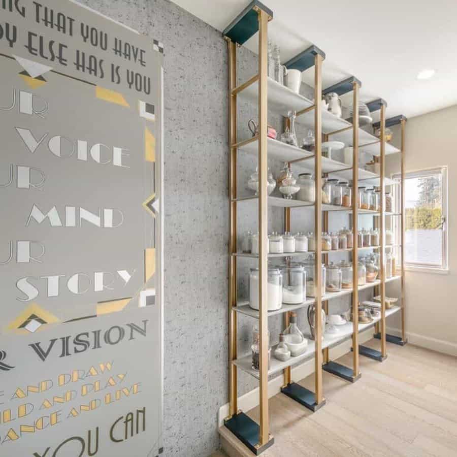 Modern pantry shelves with various jars, containers, and decor; wall art features inspirational text; bright room with natural light