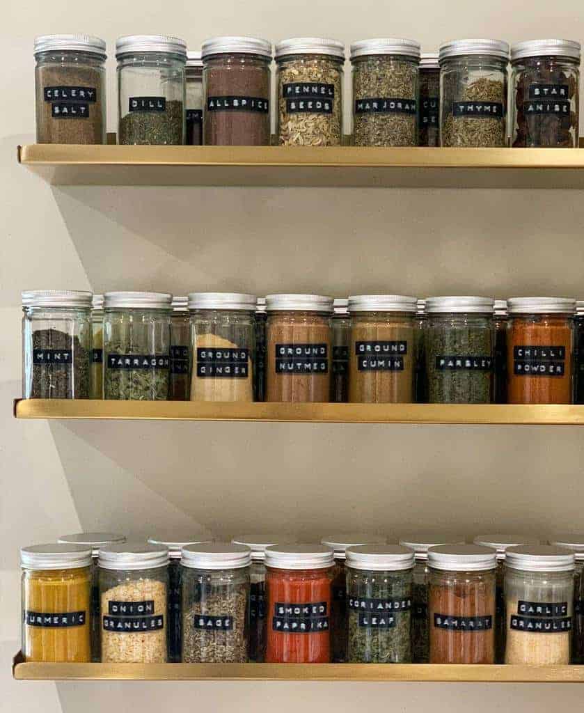 Three shelves with jars of spices, each labeled: celery salt, dill, fennel seeds, marjoram, clove, thyme, star anise, and more