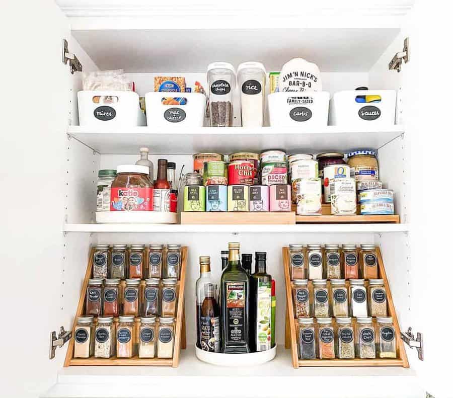 Organized pantry shelves with labeled bins, spice racks, and a turntable holding condiments, oils, and canned goods