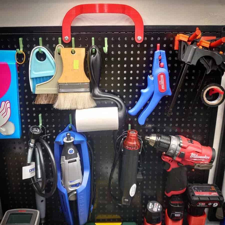 A pegboard with various tools hung on hooks, including a drill, brushes, clamps, and a wrench