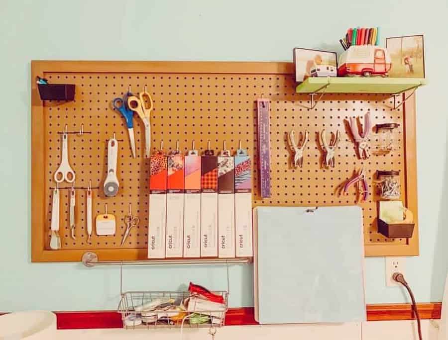 Organized pegboard with scissors, rulers, tape, pliers, and colorful files; shelf above holds a toy truck and books