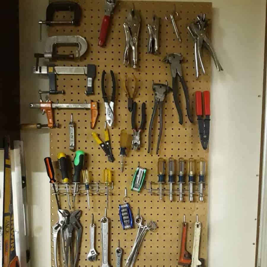 Pegboard with various hand tools, including pliers, screwdrivers, and clamps, neatly organized and hanging on hooks