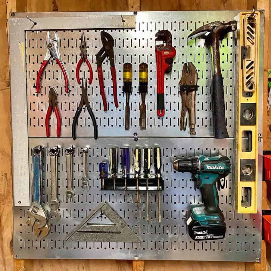 A pegboard with assorted tools: pliers, wrenches, screwdrivers, a hammer, a level, a power drill, and a square