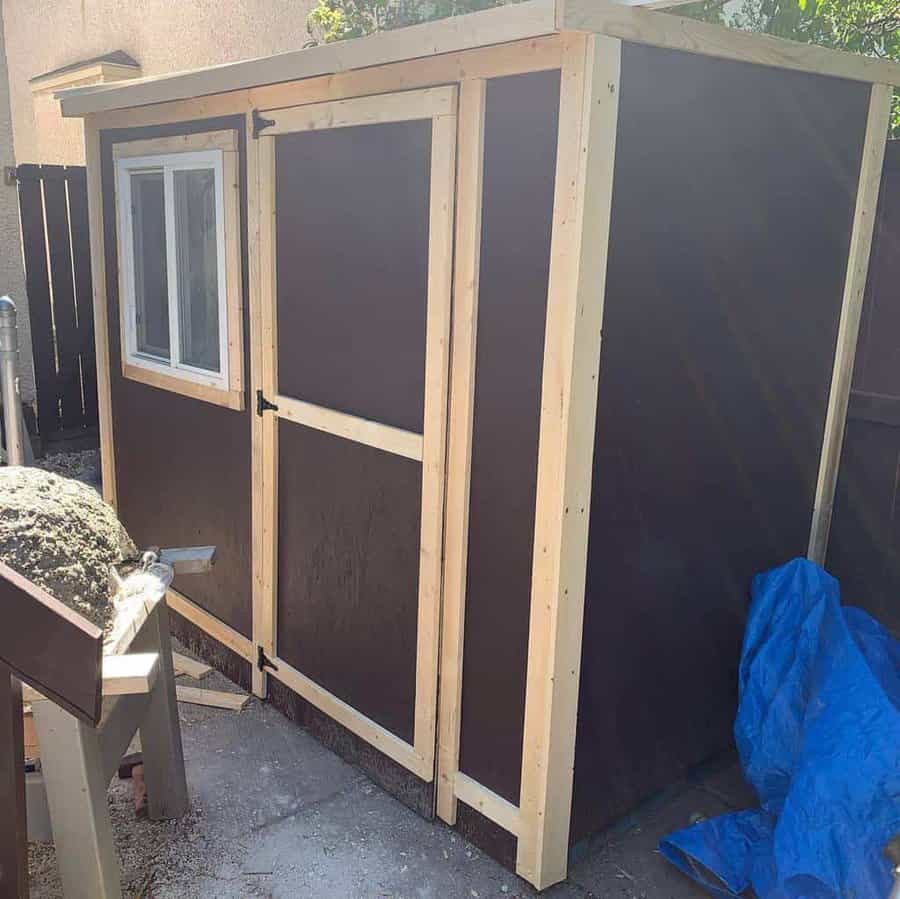 Sturdy DIY pallet shed with a framed door and window, offering a functional and stylish storage solution for any backyard space