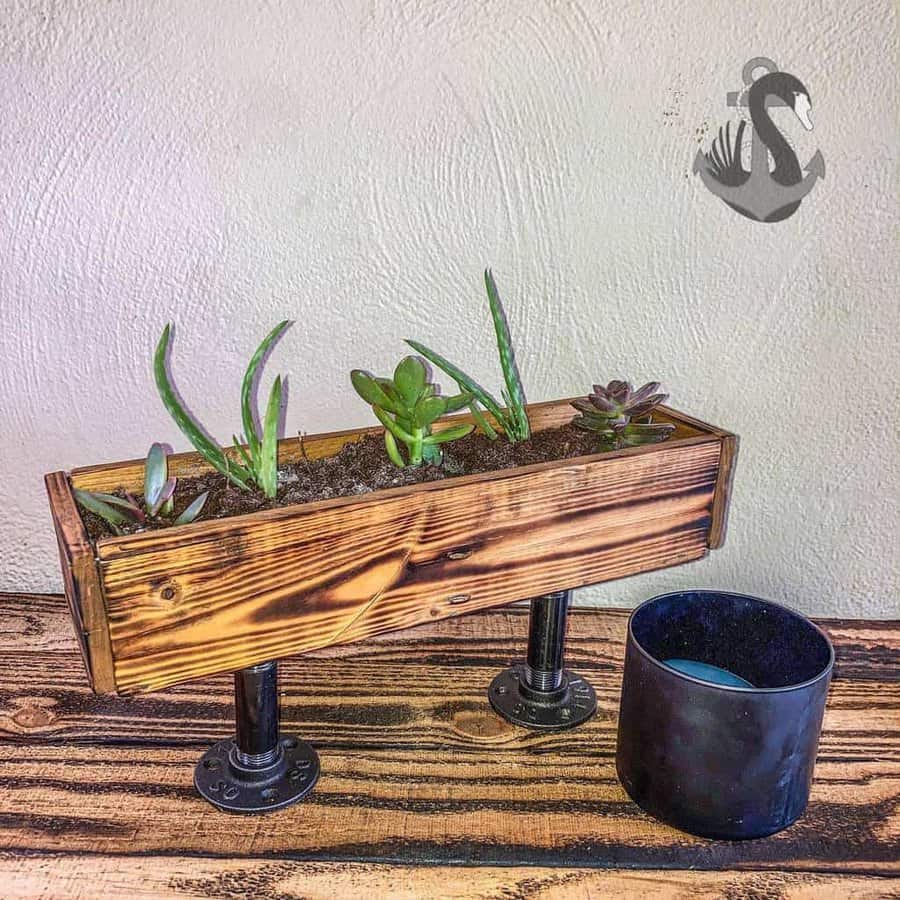 Rustic pallet wood planter with industrial pipe legs, perfect for showcasing succulents in a stylish and modern tabletop display