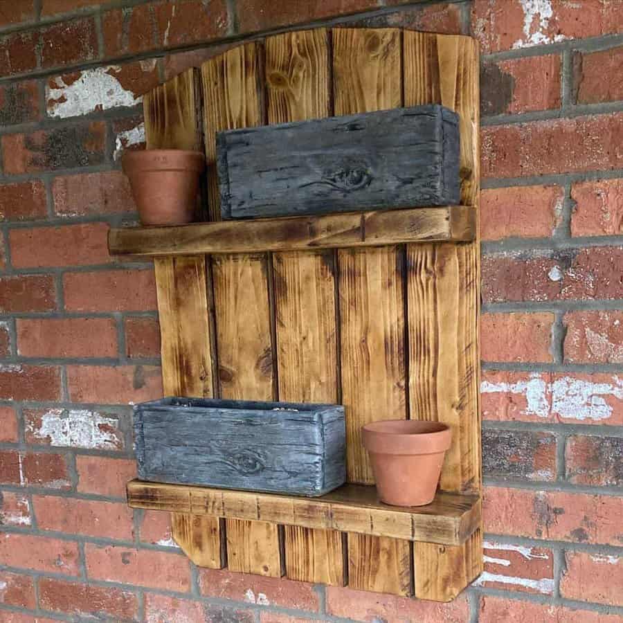 Rustic pallet wood wall shelf with a natural finish, featuring built-in planters and terracotta pots for a charming farmhouse-style display