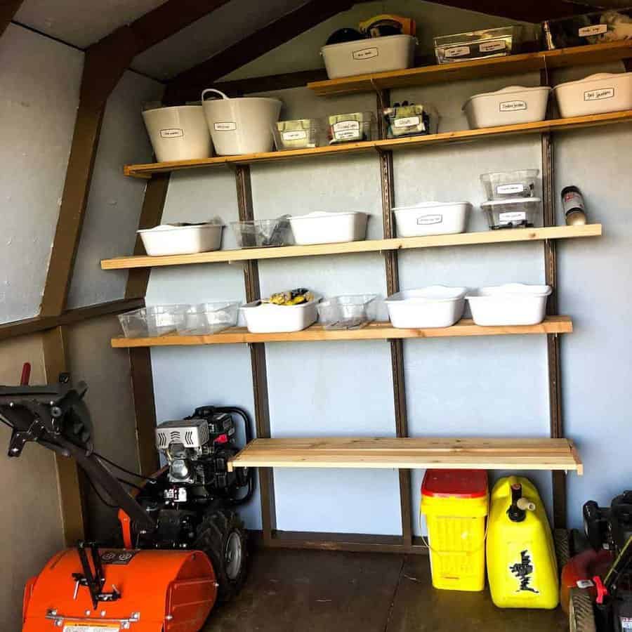 Neatly organized shed with labeled storage bins on wooden shelves, a workbench, and gardening equipment for efficient space use