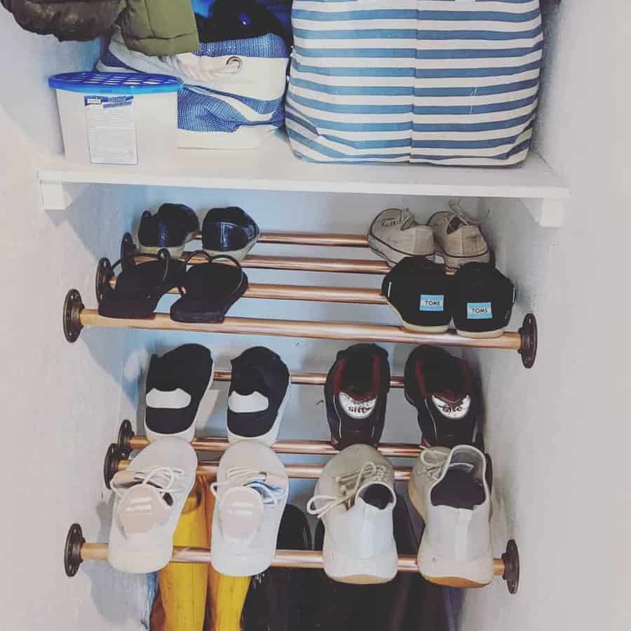 Organized closet section with shoes on racks and bags on a shelf above