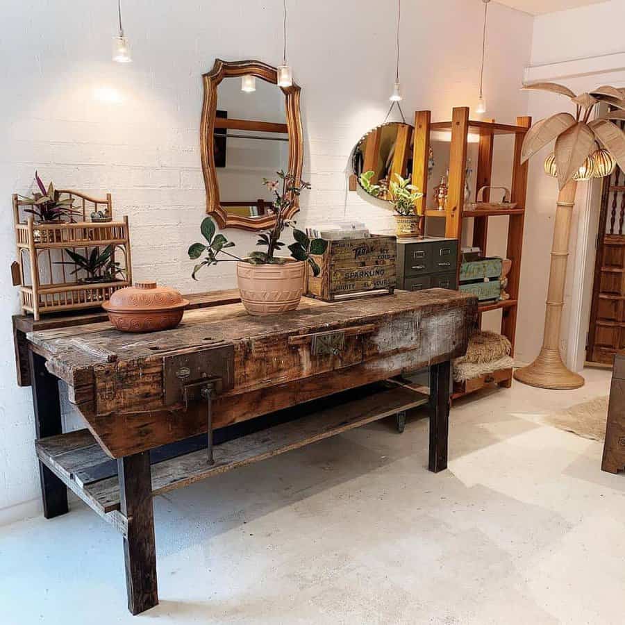 Vintage wooden workbench with potted plants, a mirror above, wooden shelves, and hanging lights in a cozy, rustic room