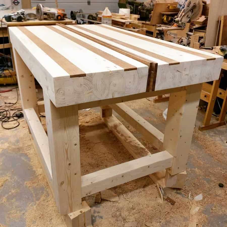 A wooden workbench under construction in a workshop, surrounded by tools and wood shavings