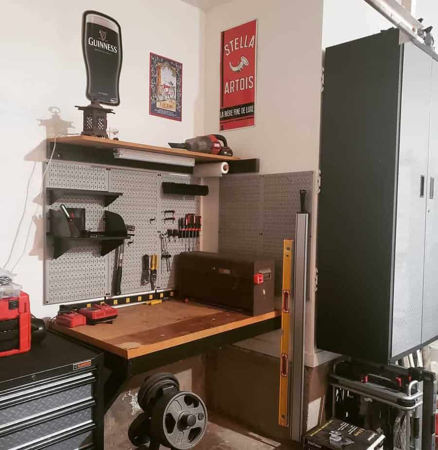 A garage workshop with tools on a pegboard, a workbench, toolboxes, and wall decoration with Guinness and Stella Artois signs