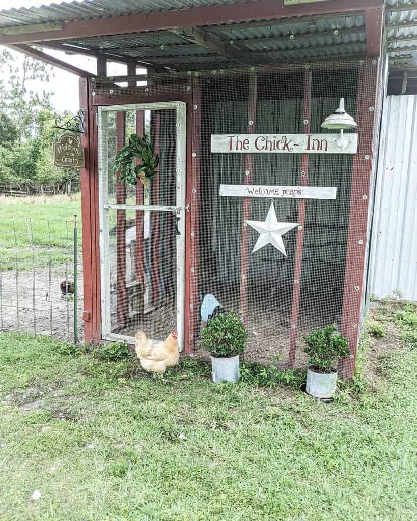 A rustic chicken coop labeled "The Chick Inn" with a white star, plants, and a chicken nearby