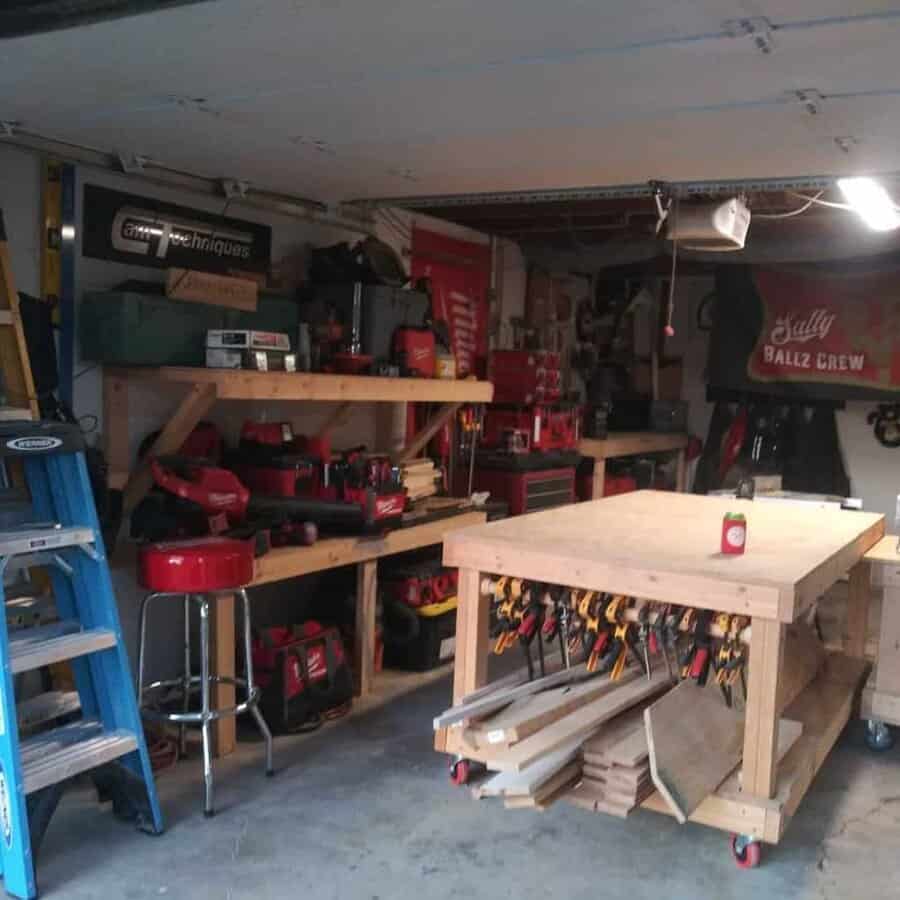 A workshop with wooden shelves, tools, a workbench with clamps, a red stool, a ladder, and various equipment organized neatly