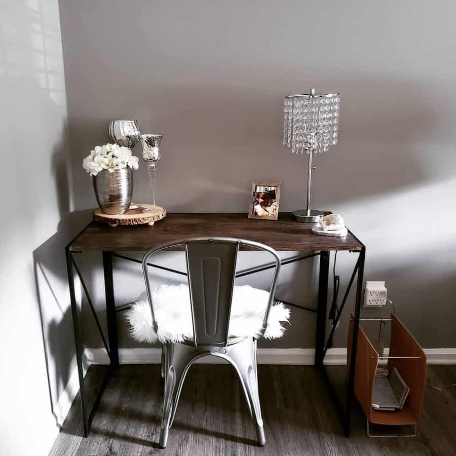 Minimalist desk setup featuring a metal chair, lamp, and decor against gray walls and on a wooden floor