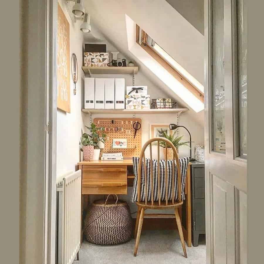 Cozy attic workspace with a wooden desk, chair, plants, and a skylight; pegboard organizer on the wall, and a basket on the floor