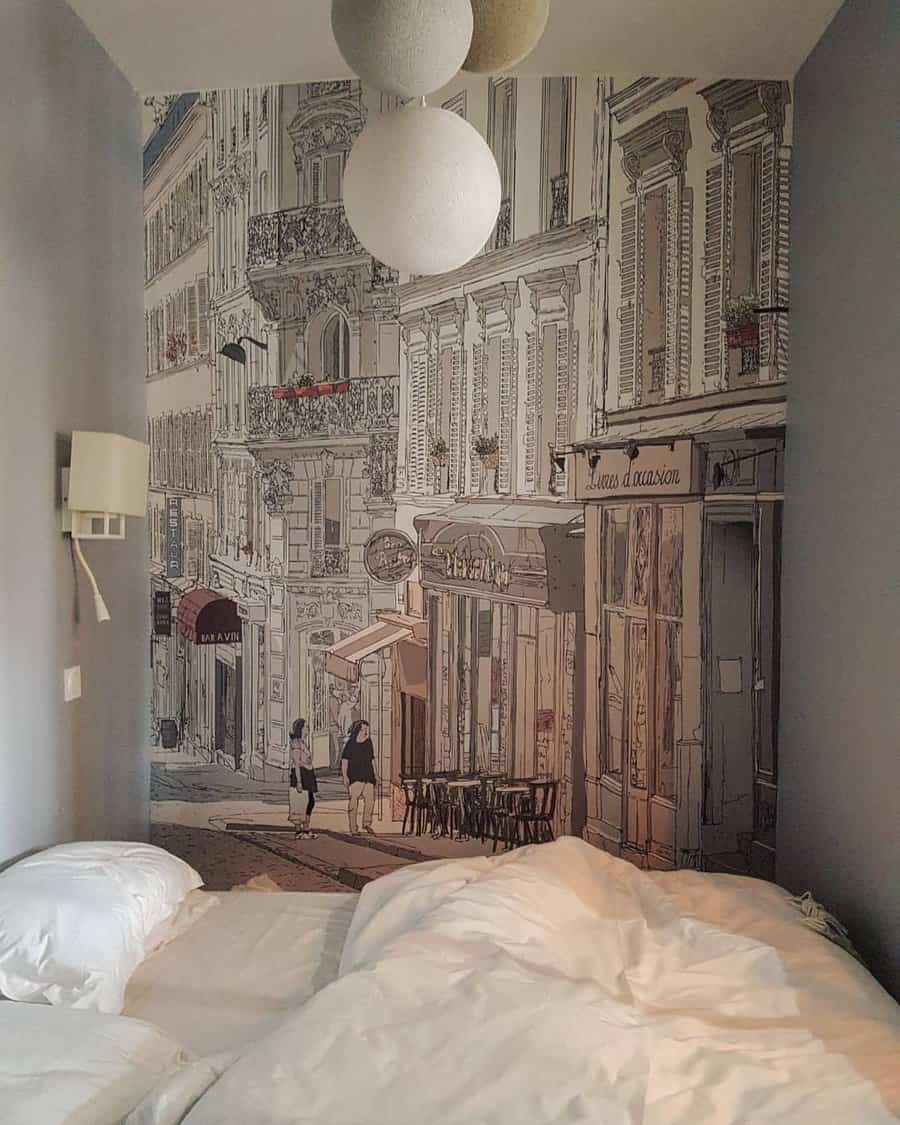 Interior of a bedroom with a mural featuring a European street scene behind unmade twin beds