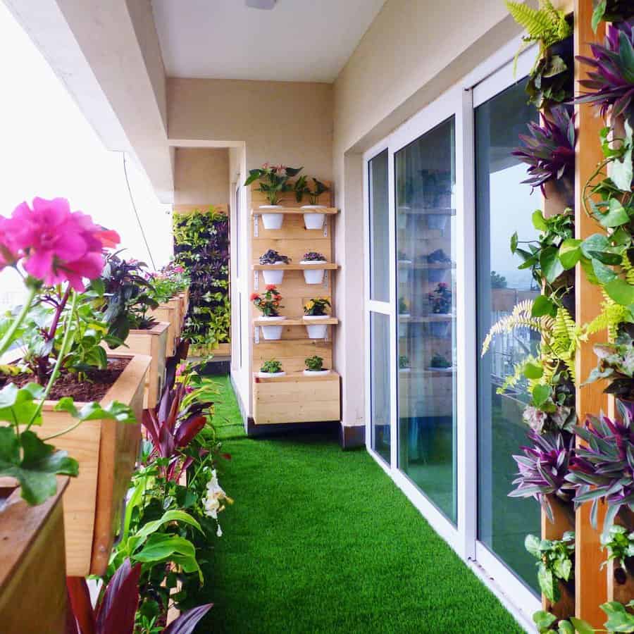 Lush balcony with artificial grass, vertical garden walls, wooden planters, and potted plants creating a vibrant green outdoor space